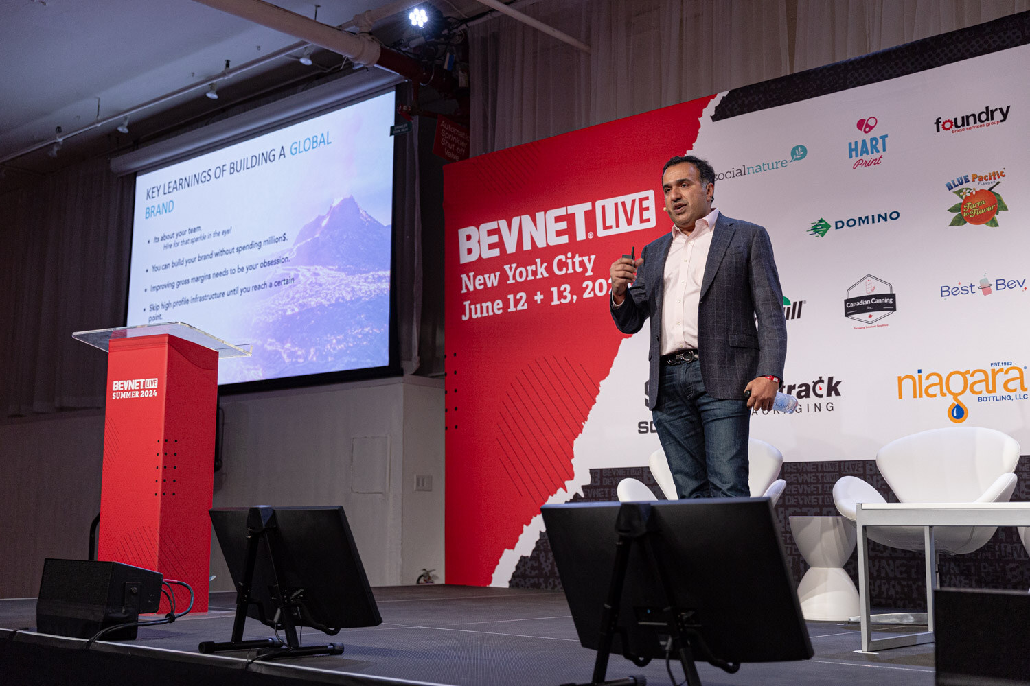 Speaker stands on stage beside a slide on key learnings of building a global brand.