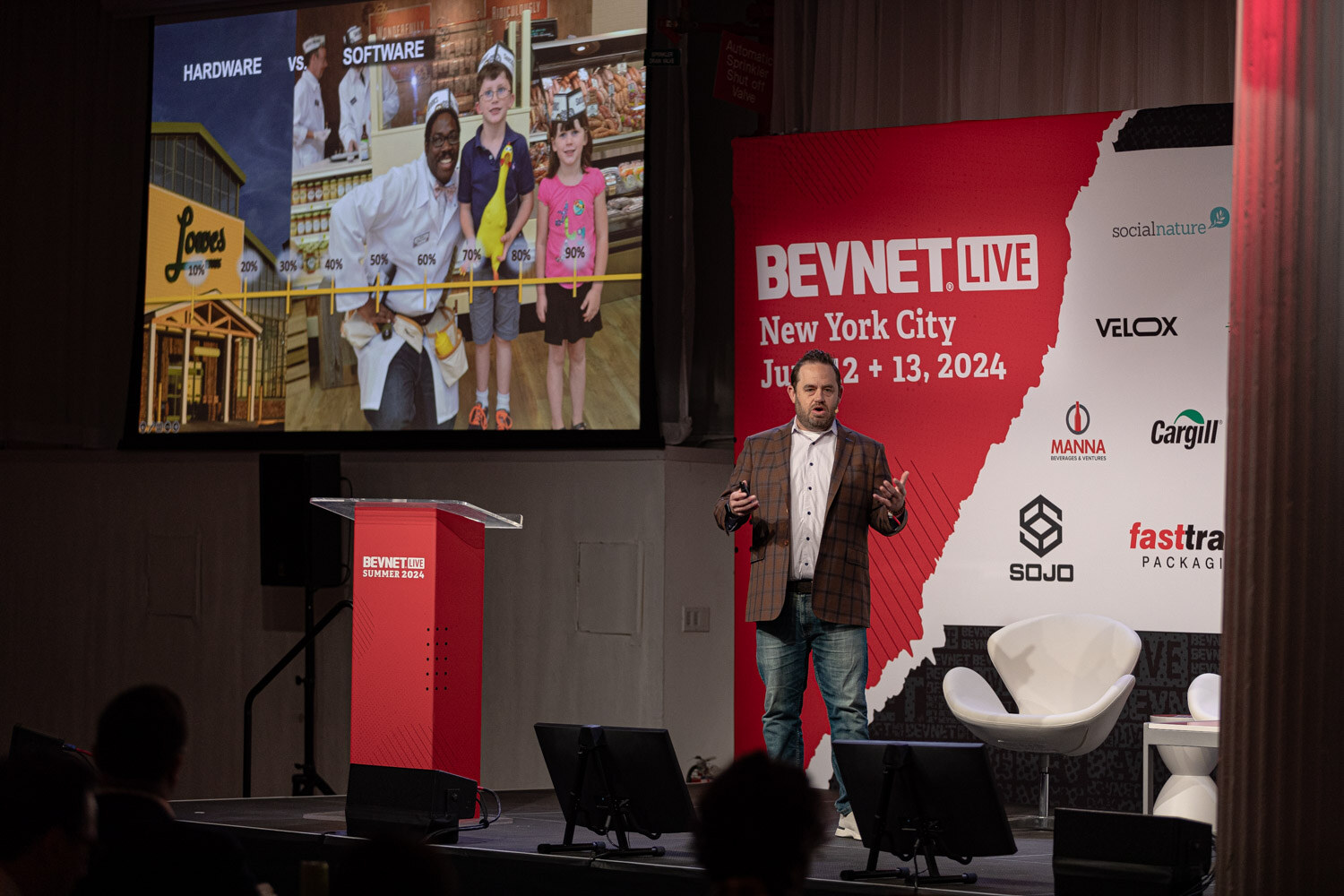 Wide view of the retailer guest on stage next to a slide with photos of employees.