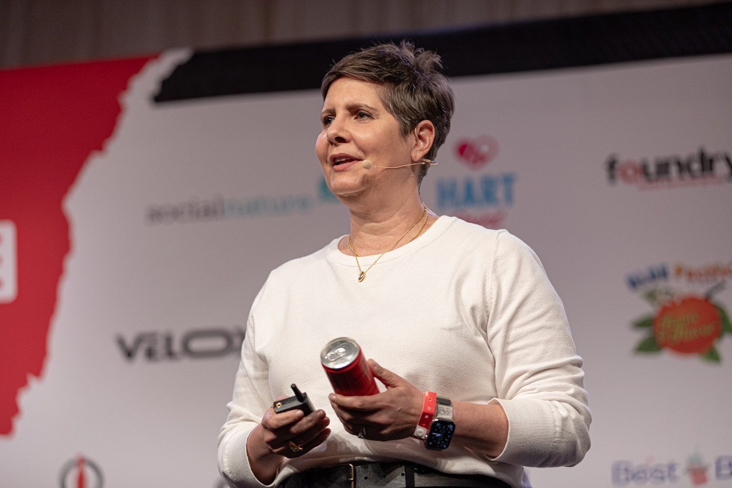 Speaker in a white sweater holds a red can during Customer Centric Brand Strategy.