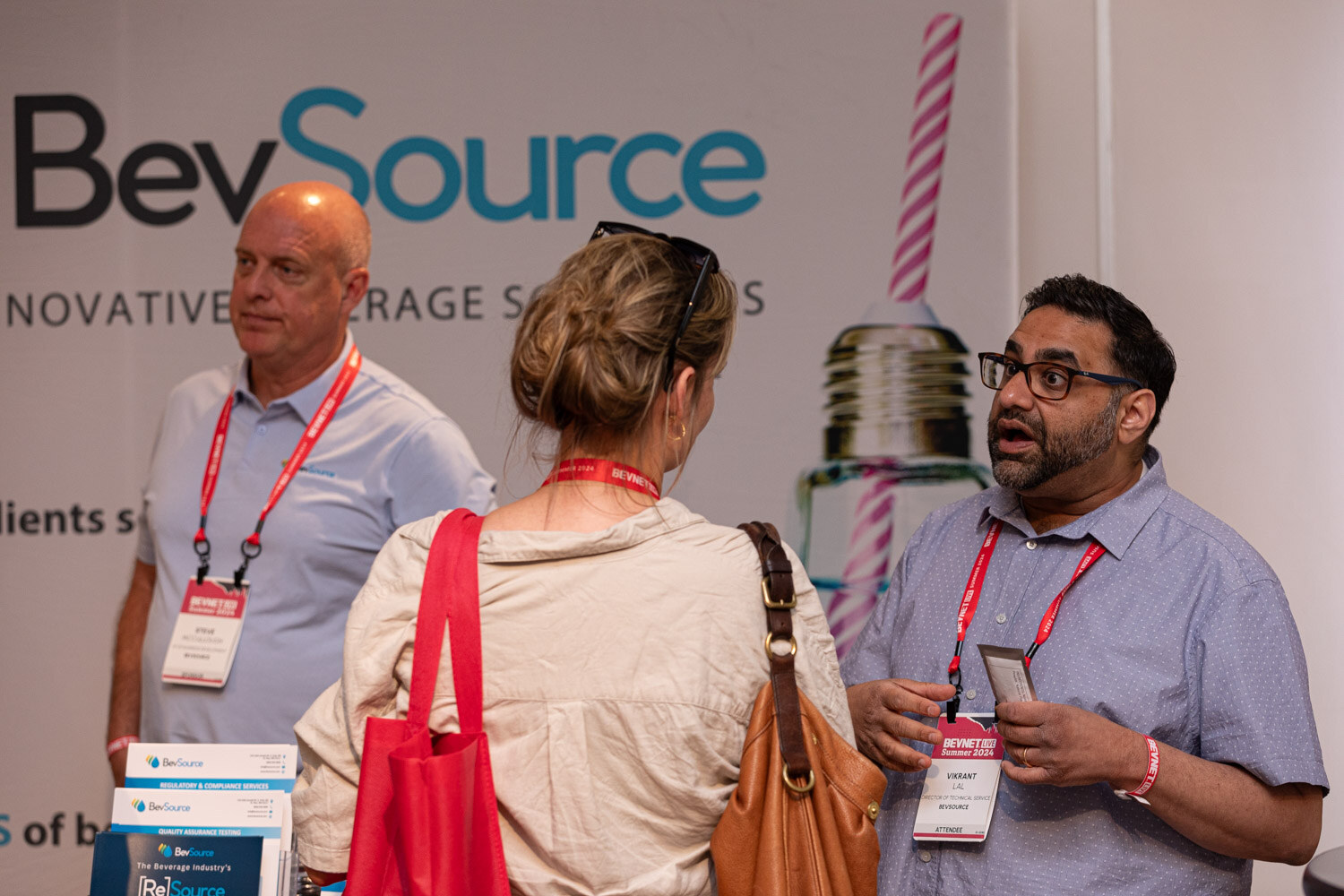 Representatives talk with an attendee at the BevSource booth.