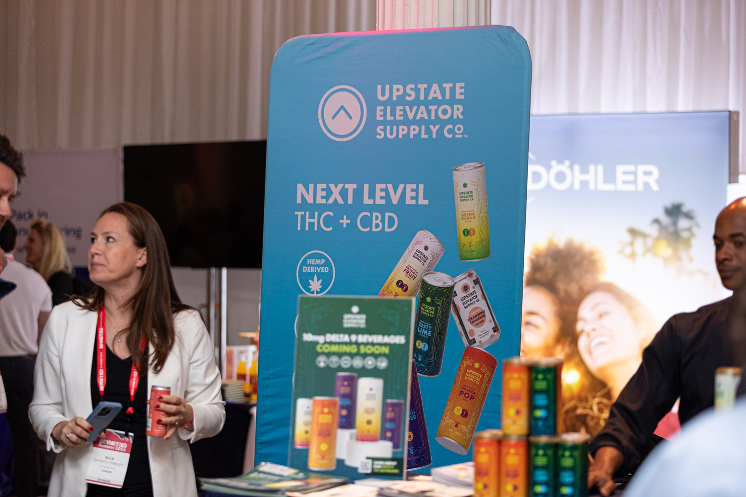 Attendee at the Upstate Elevator Supply Co. booth next to a display of canned drinks.