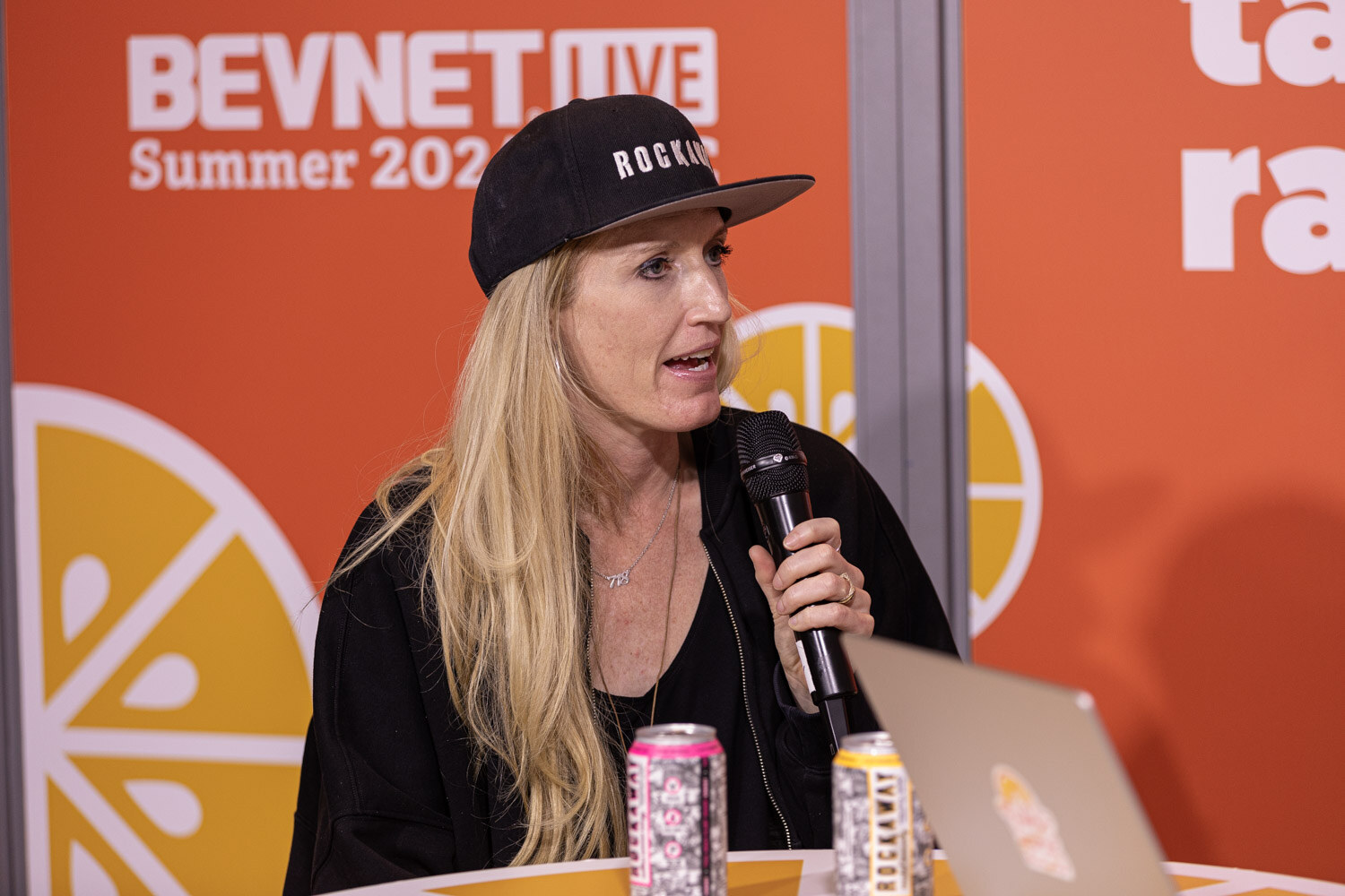 Guest in a black cap speaks into a microphone beside two cans at the Taste Radio livestream.