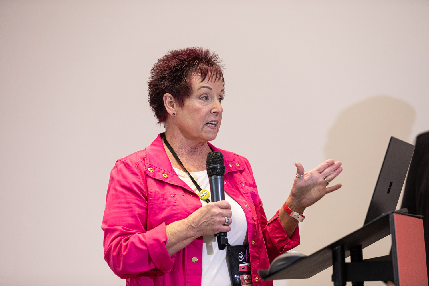 Workshop presenter gestures while speaking into a handheld microphone.