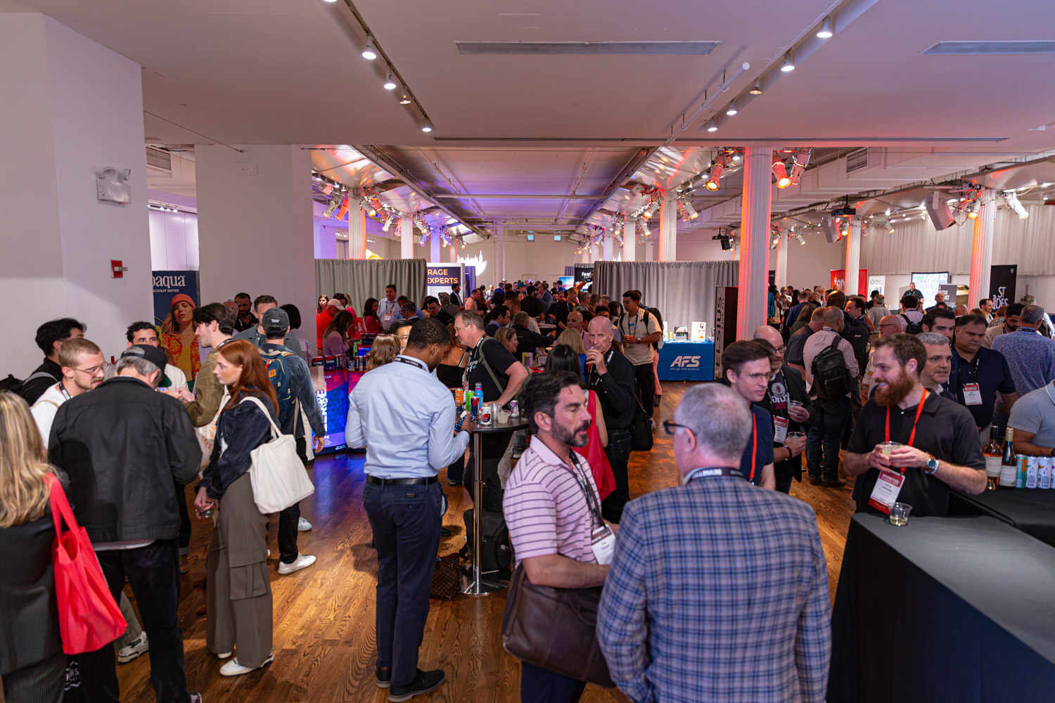 A wide view of a long hall filled with attendees and exhibitor booths.