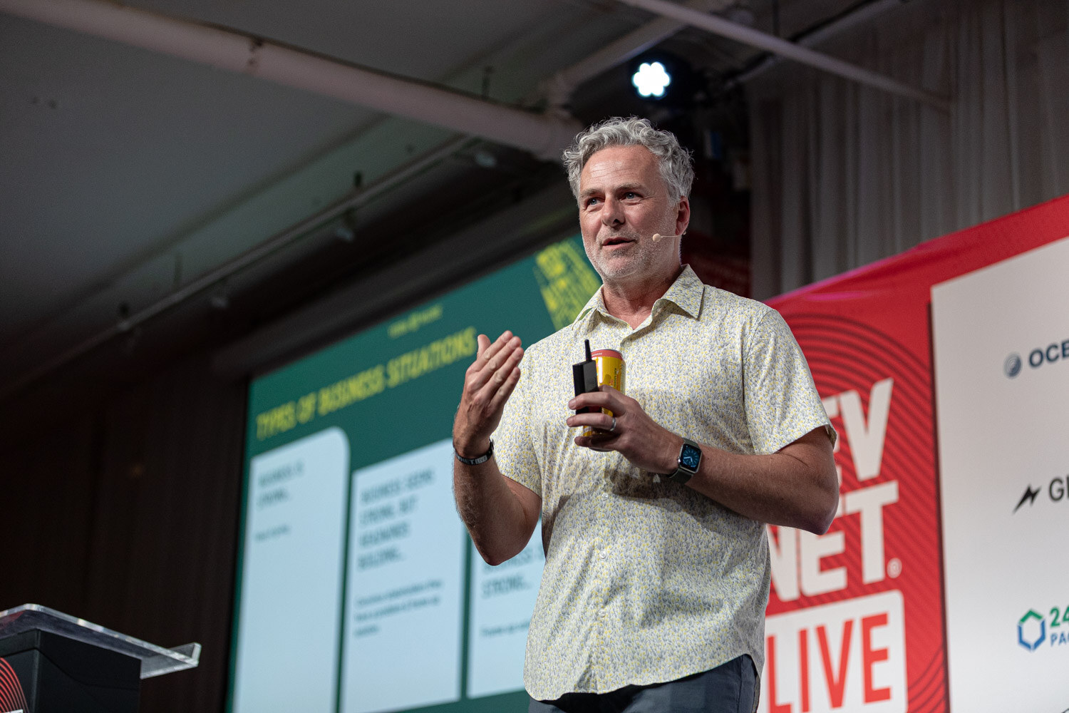 A man in a patterned shirt holds a can and gestures in front of a green slide titled Types of Business Situations.