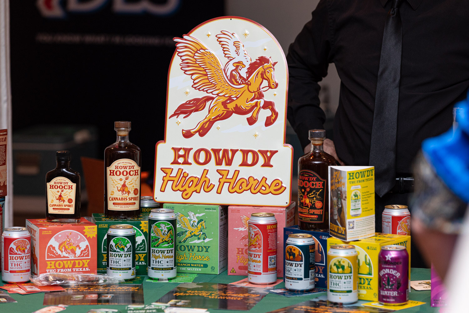 A tabletop with Howdy High Horse cans, bottles and boxes under a Howdy High Horse sign.