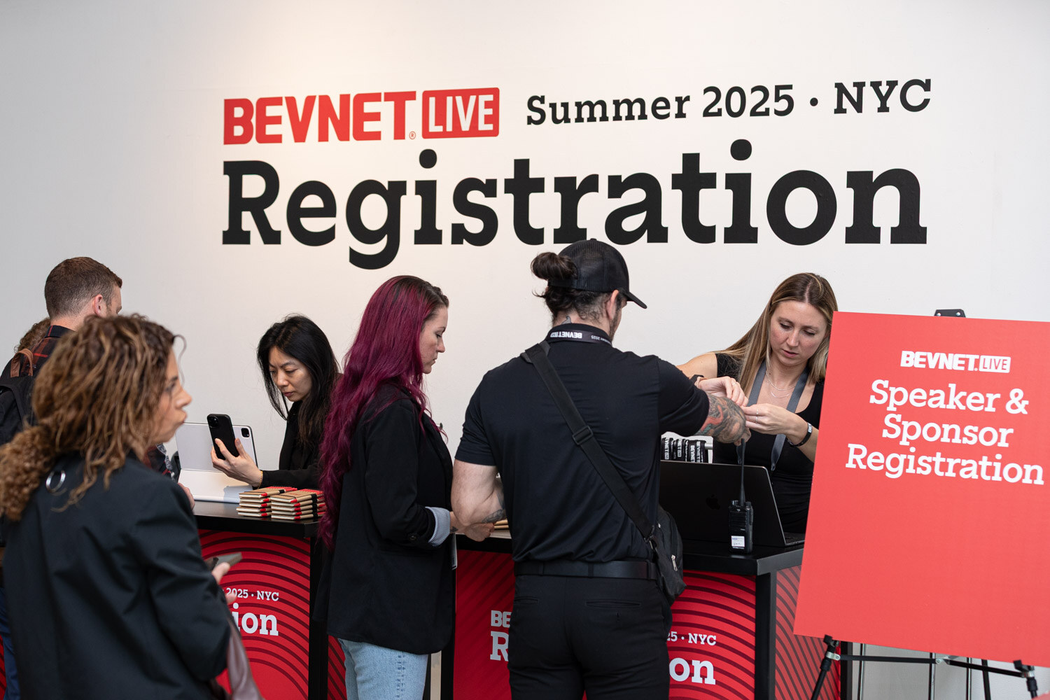Several attendees and staff at a registration desk under a BevNET Live Summer 2025 NYC Registration sign.