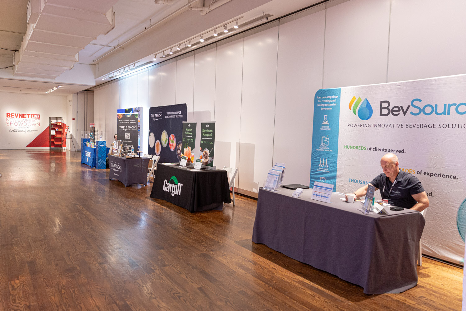 A hardwood-floored hall with exhibitor tables for Cargill and BevSource.