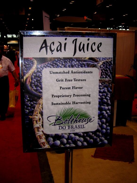 Framed sign for Bolthouse do Brasil Açai Juice showing açai berries and claims including unmatched antioxidants and sustainable harvesting, on the IFT 2007 show floor.