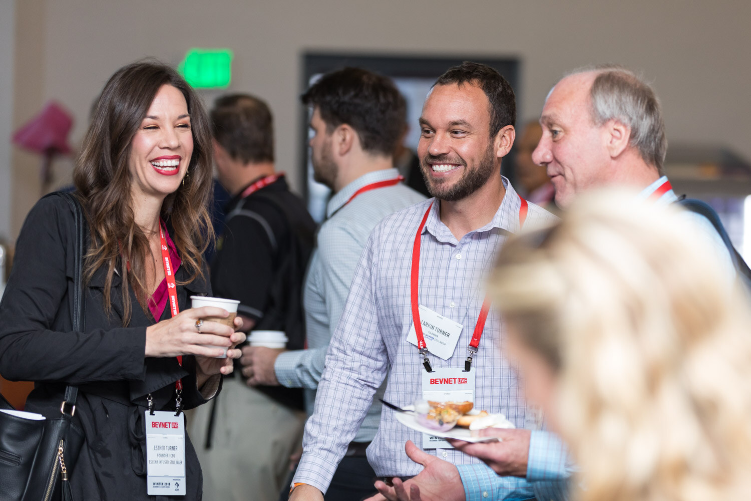 Smiling woman and men holding coffee cups and plates at a morning networking breakfast.
