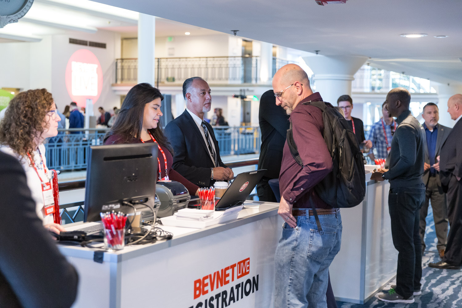 Attendees at a desk labeled BevNET Live Registration with staff at computers.
