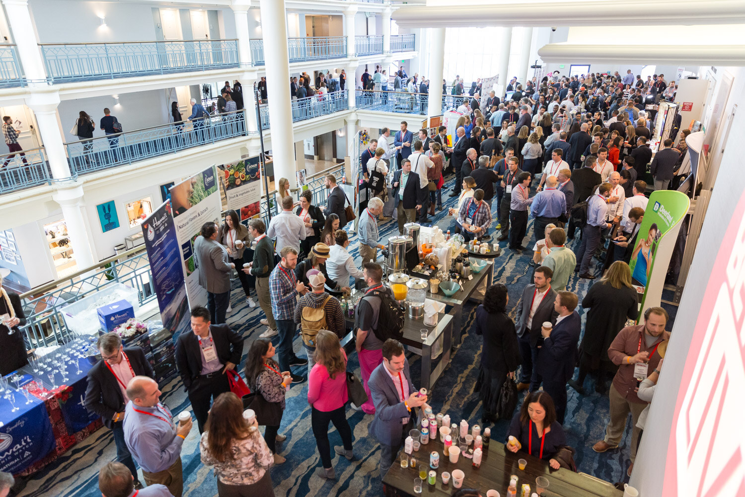 High angle view of a crowded hotel atrium with attendees and tabletop exhibits.
