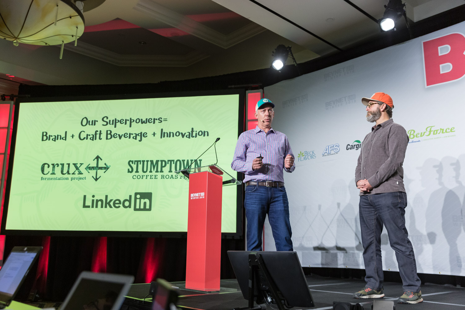 Two men standing near a podium and a green slide titled Our Superpowers.