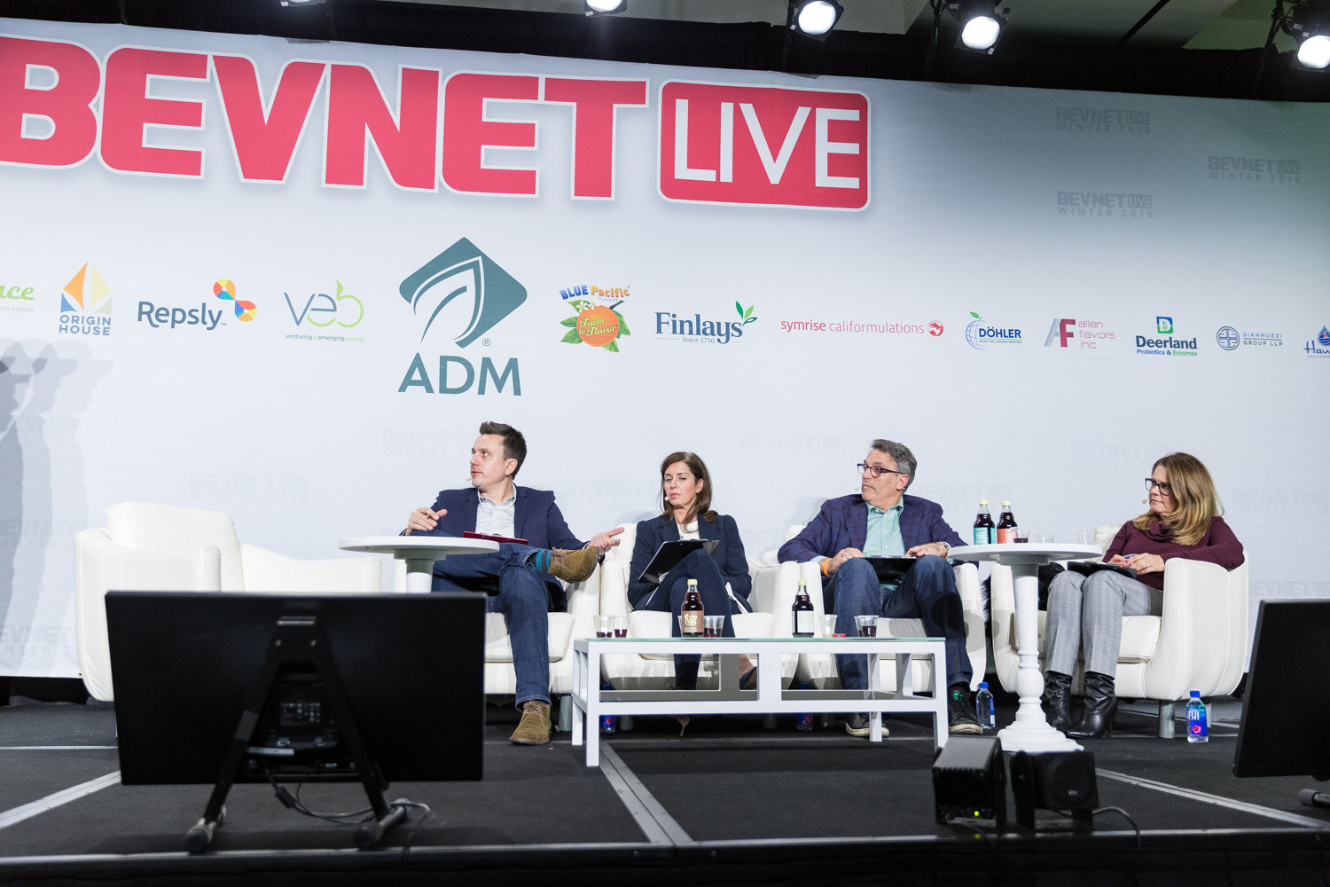 Four people seated on stage in white chairs under a BevNET Live backdrop.