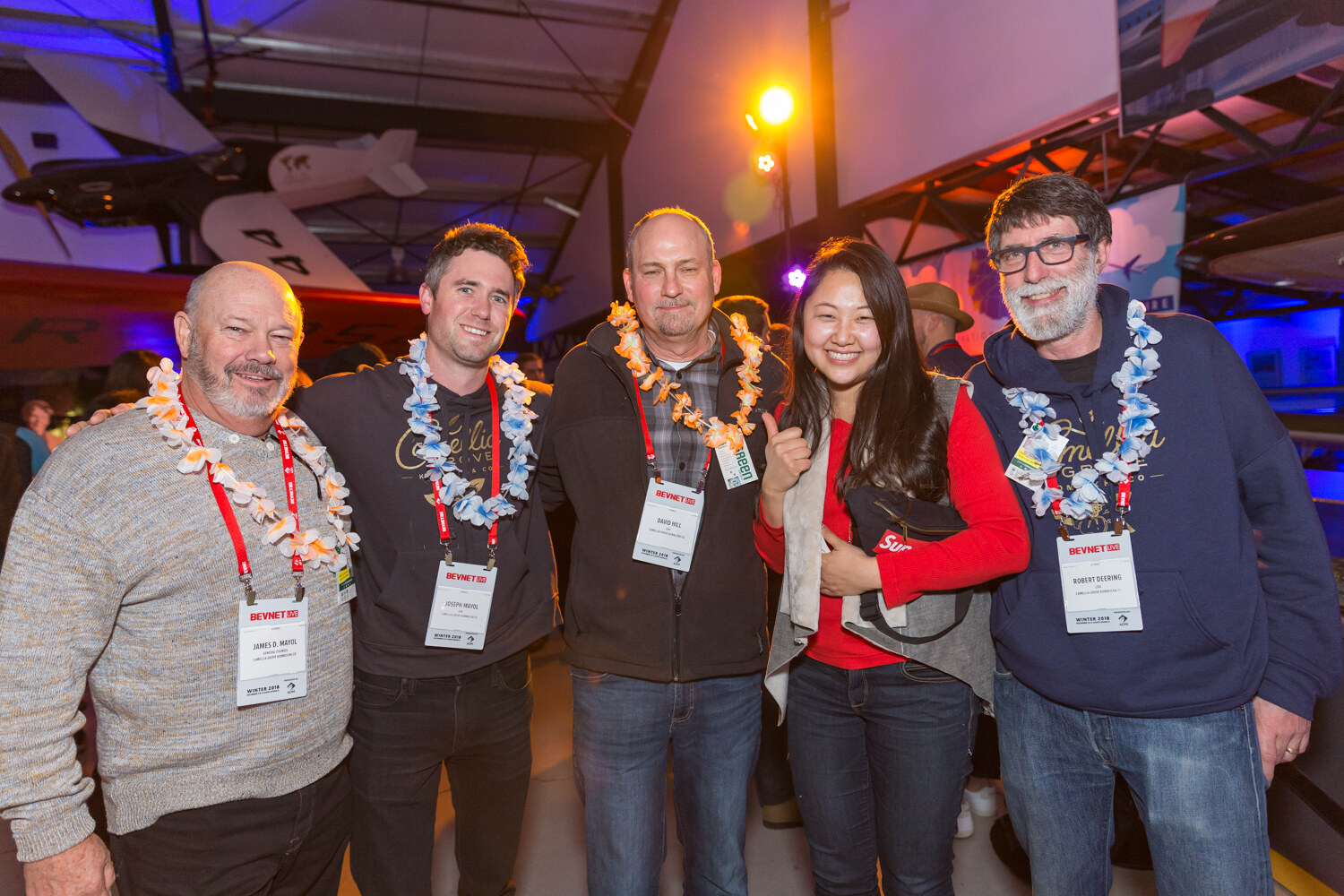 Group of five attendees in leis and lanyards smiling for the camera.