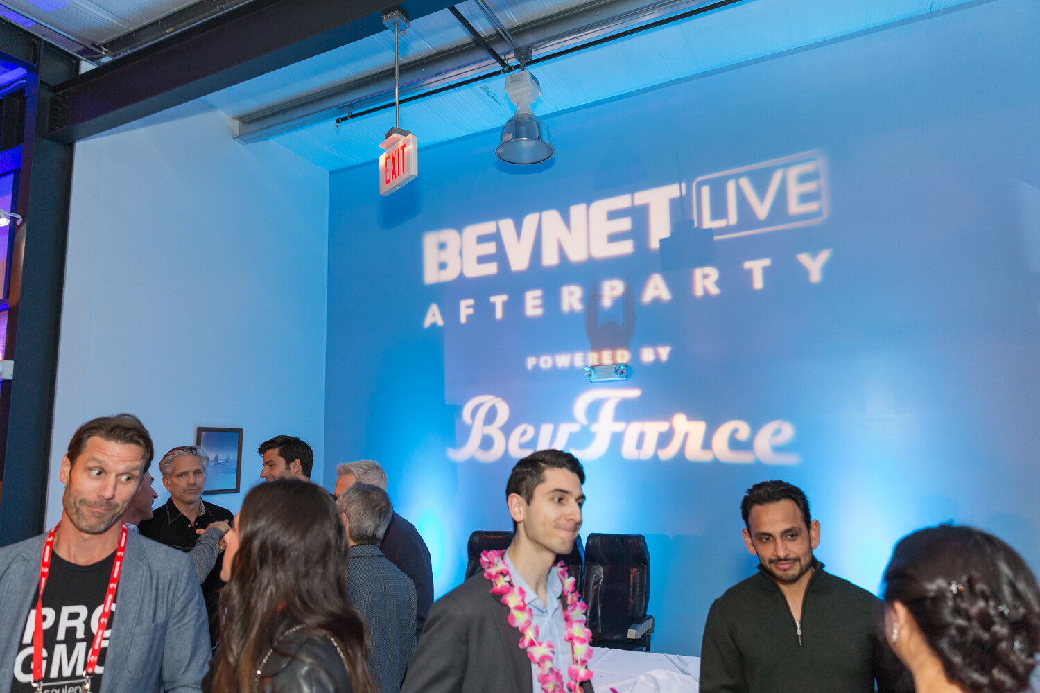 Group of guests in front of a blue sign reading BevNET Live Afterparty Powered by BevForce.