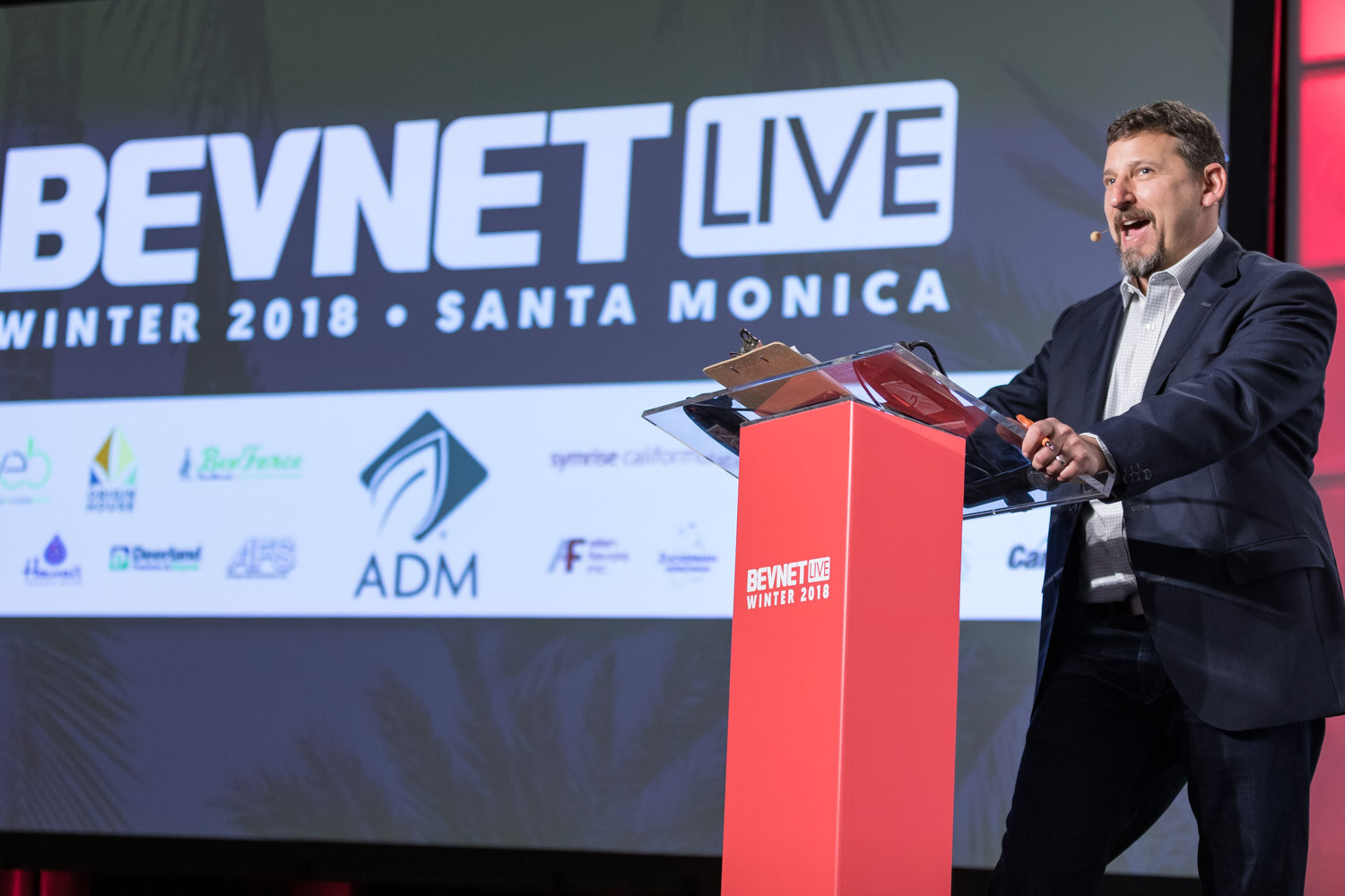 Man at a clear podium with a lit screen reading BevNET Live Winter 2018 Santa Monica behind him.