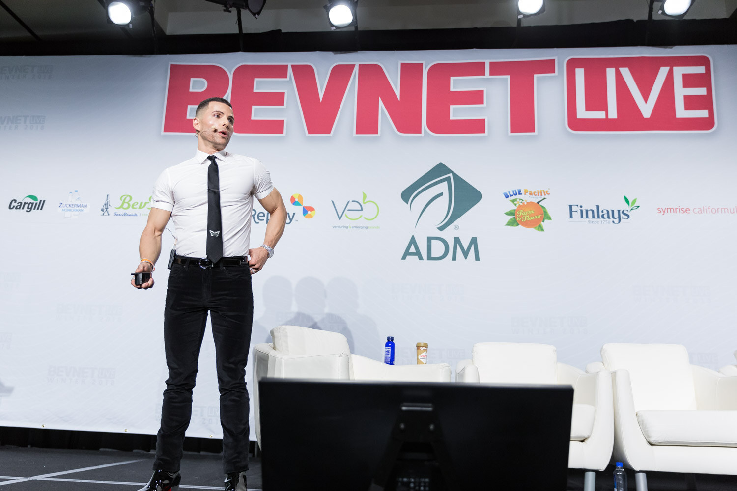 Man in a white shirt and black tie standing on the main stage in front of a BevNET Live backdrop.