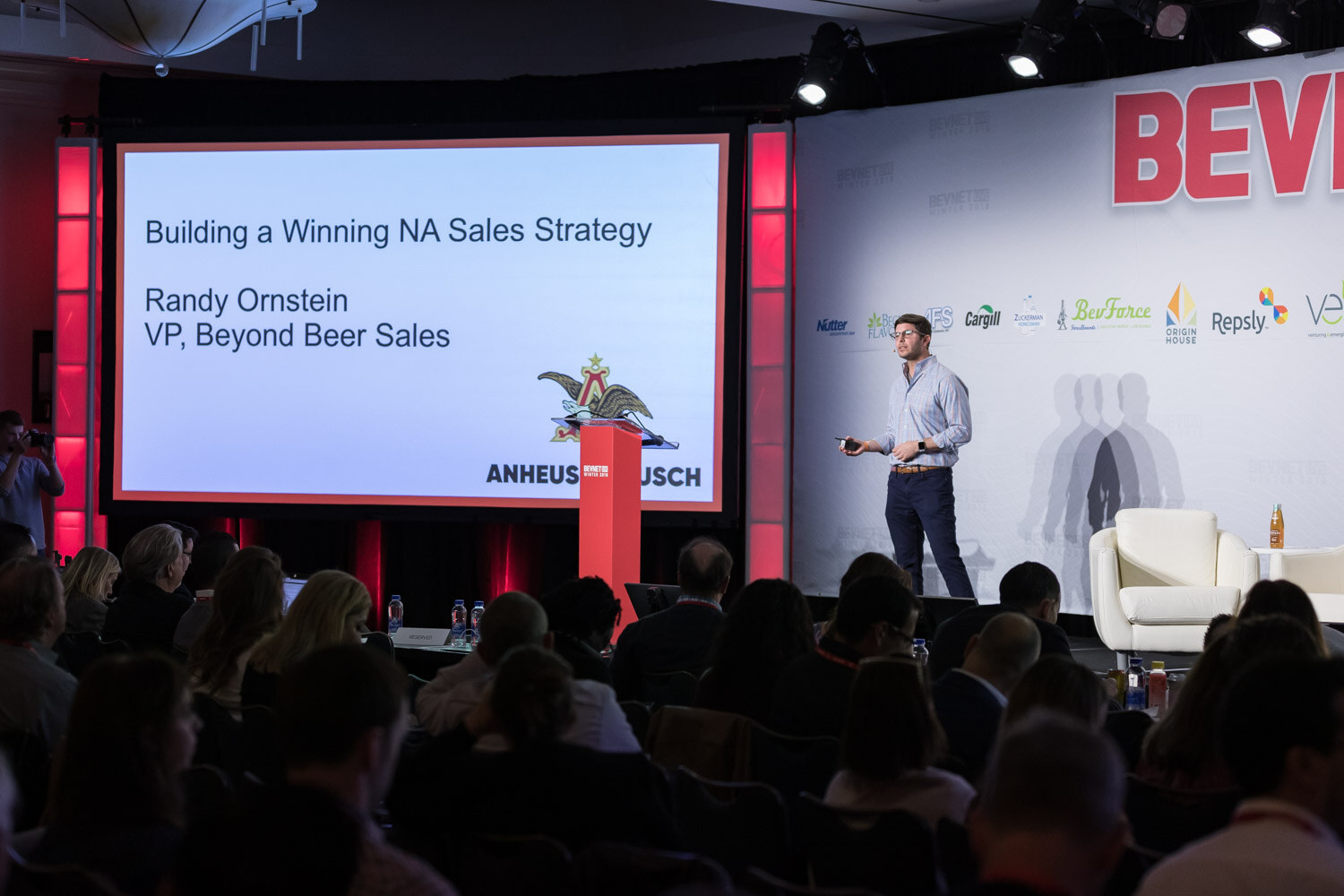 Man at a podium on stage in front of a screen reading Building a Winning NA Sales Strategy with an Anheuser-Busch logo.