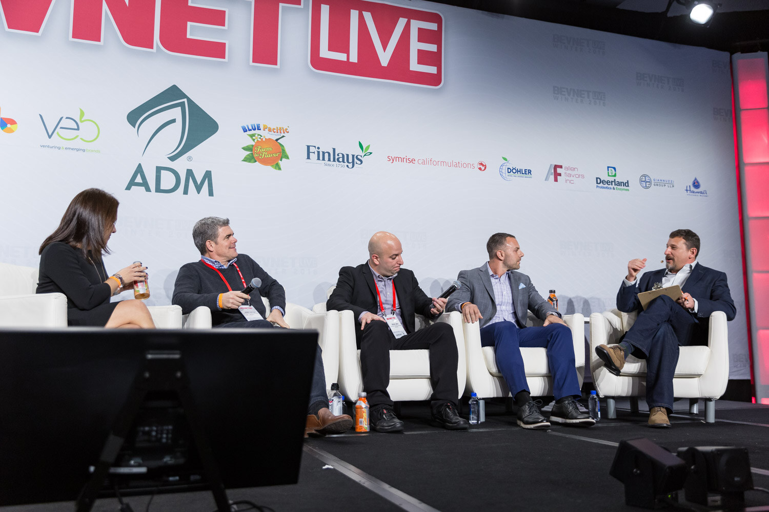Five people seated on a stage in white chairs in front of a BevNET Live backdrop.