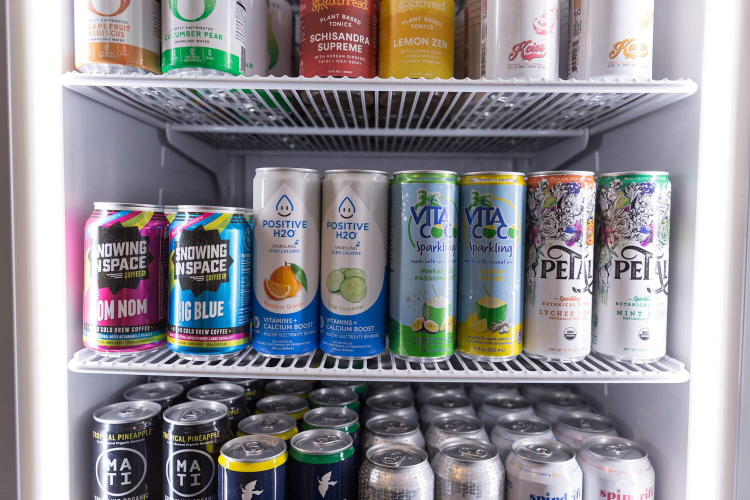 Glass cooler door shelves lined with colorful canned drinks.