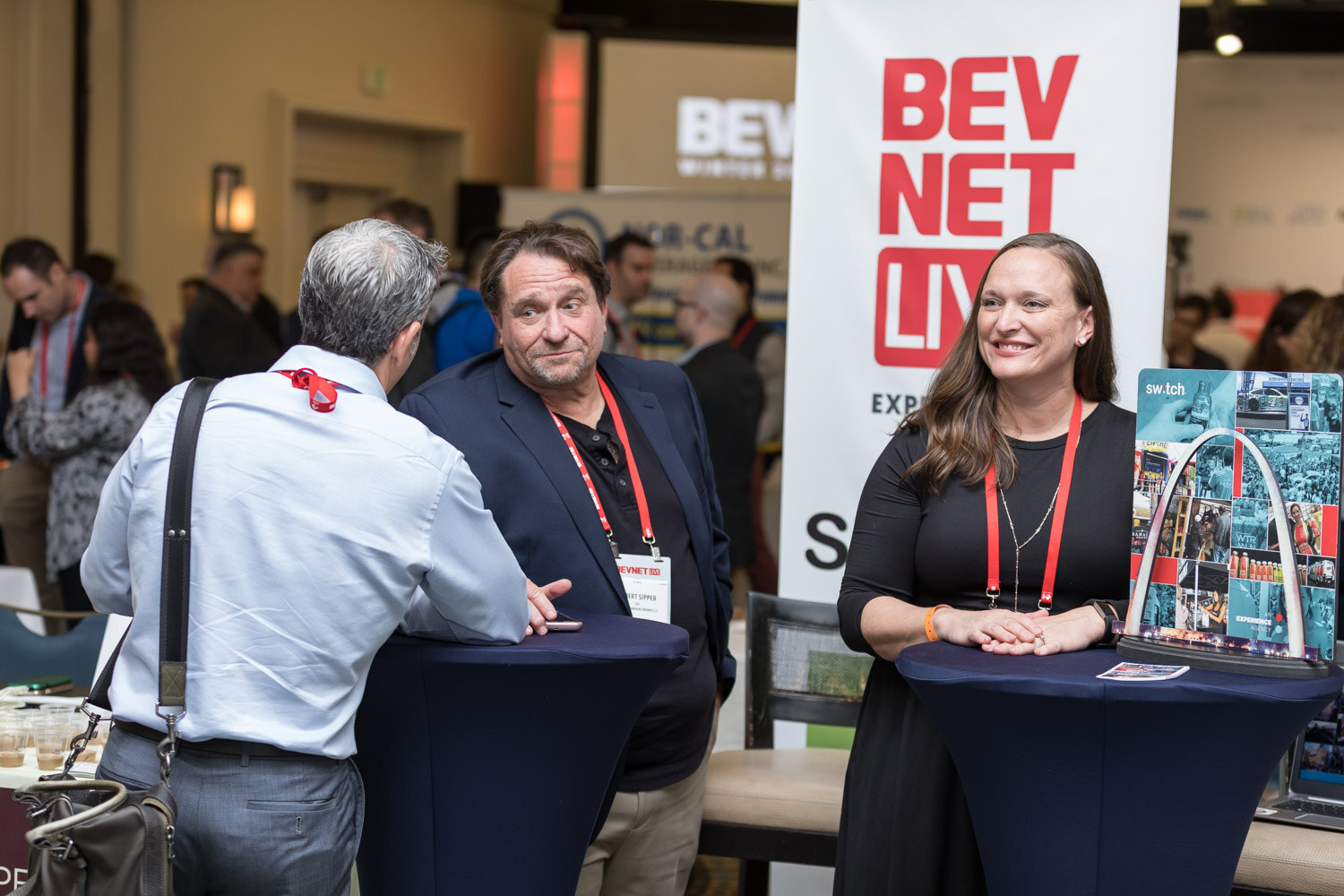 Three people at a tall table beside a BevNET Live banner.
