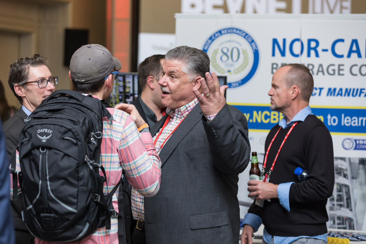 Several people talking in front of a Nor-Cal Beverage Co. contract manufacturing sign.