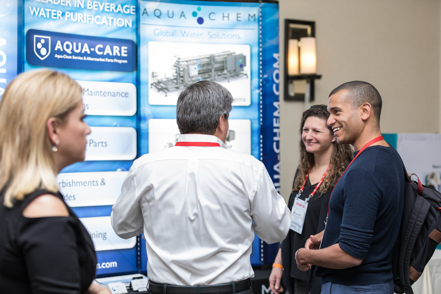 Group of people talking in front of an Aqua-Care Aqua Chem display.