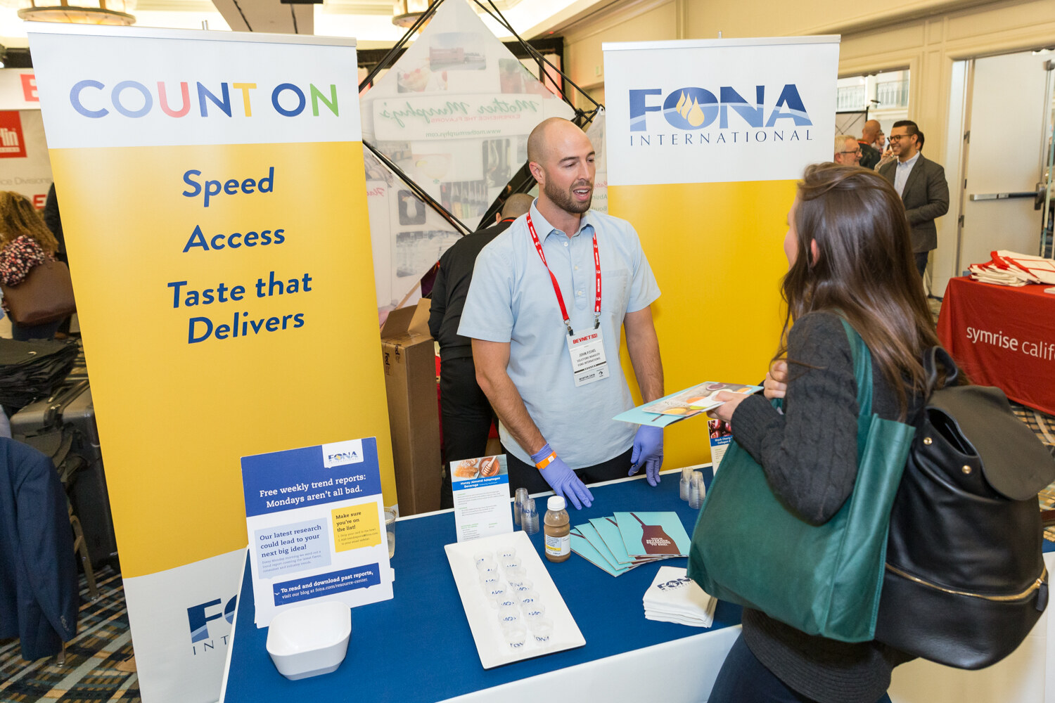 Man in gloves behind a sampling table in front of a Count On Fona banner.