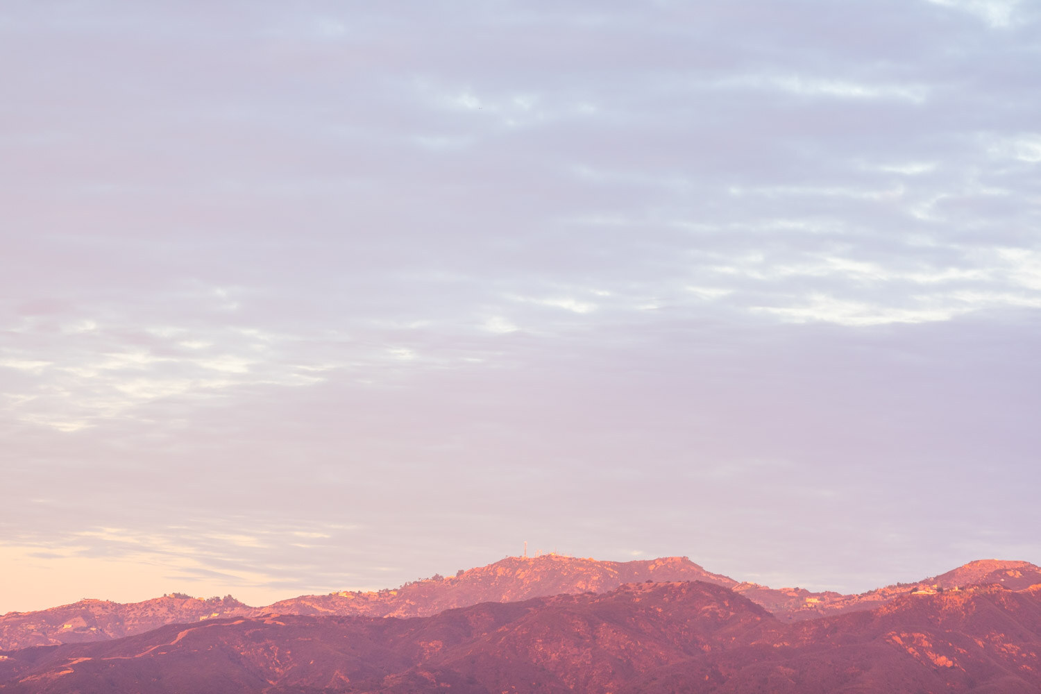 Distant mountain ridge under a pastel pink and lavender morning sky.