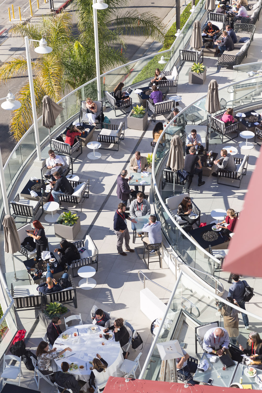 High angle view of people seated at round tables on an outdoor terrace.