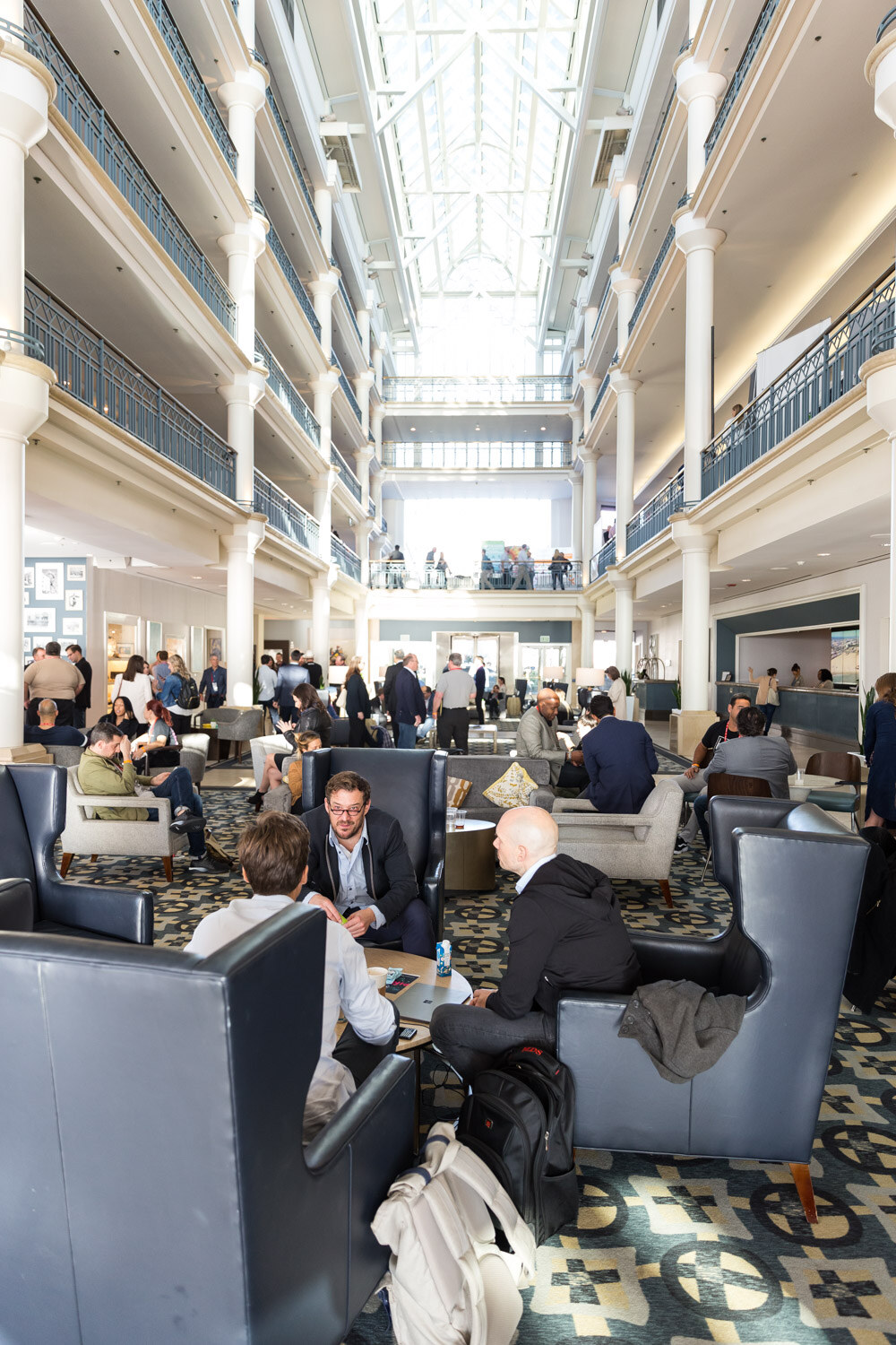 Tall hotel atrium with lounge chairs and attendees below.