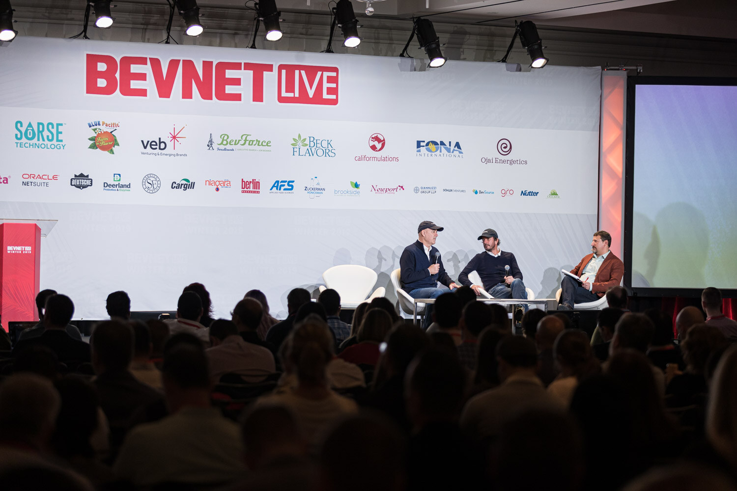 View from the audience of three people seated on a stage in front of a BevNET Live backdrop.