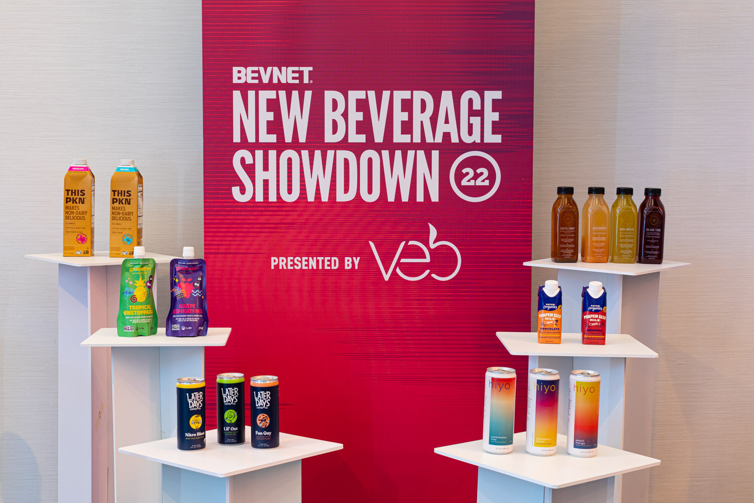 White display risers holding cartons, pouches, bottles and cans in front of a red banner reading BevNET New Beverage Showdown 22 presented by veb.