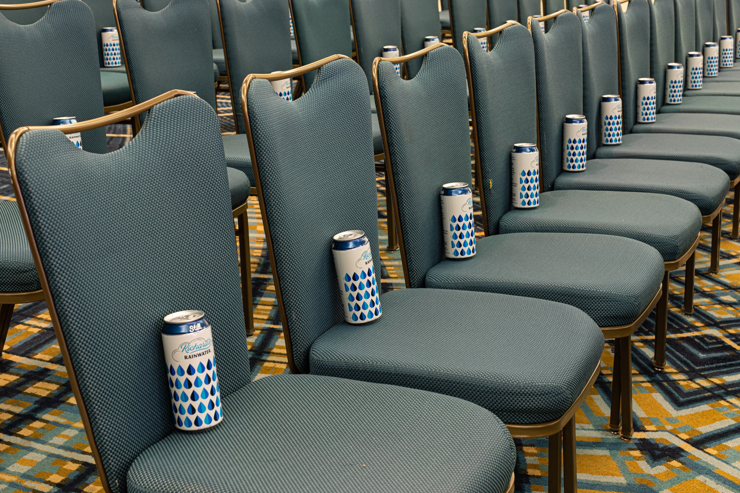 Rows of gray-green chairs with a blue-and-white patterned Richard's Rainwater can on each seat.