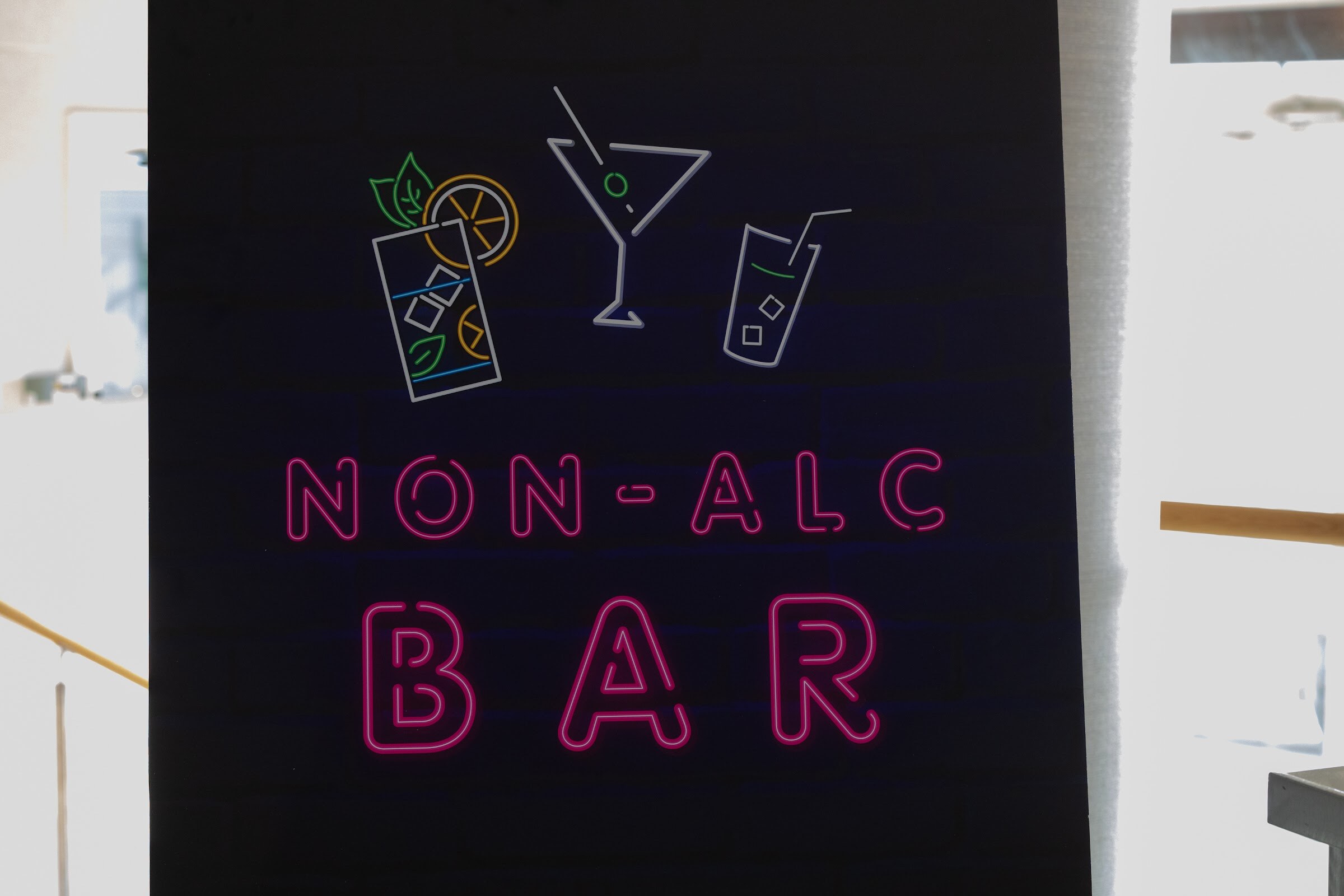 A black sign with pink neon lettering reading Non-Alc Bar and cocktail glass outlines.
