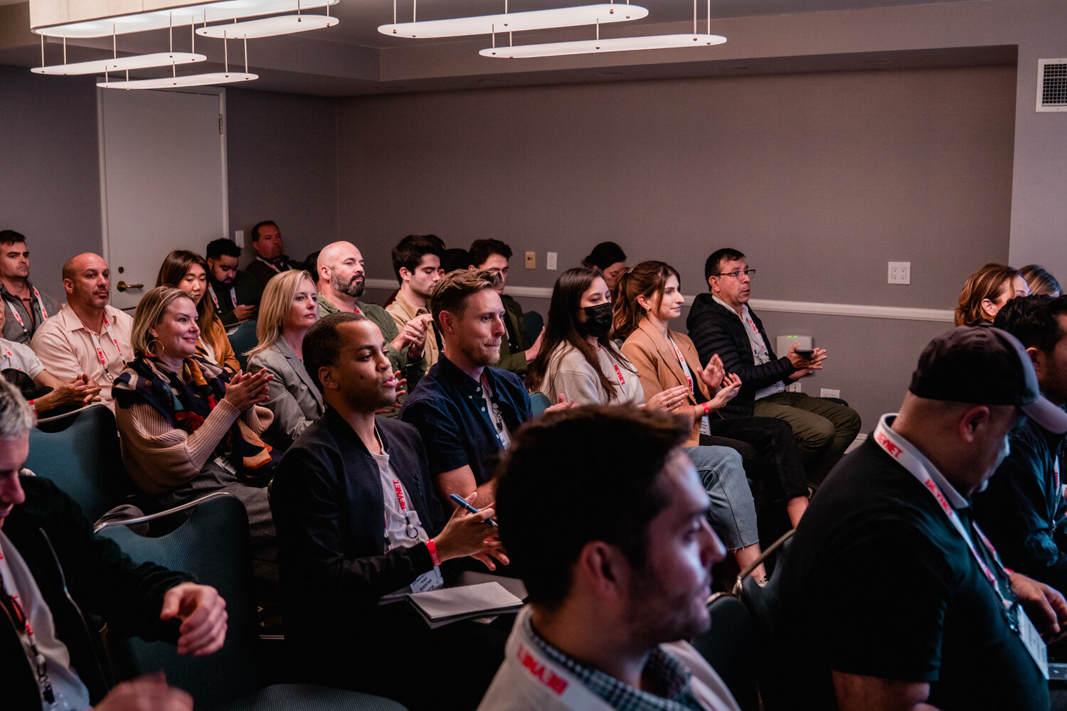 Rows of attendees wearing BevNET lanyards, several clapping, in a hotel meeting room.