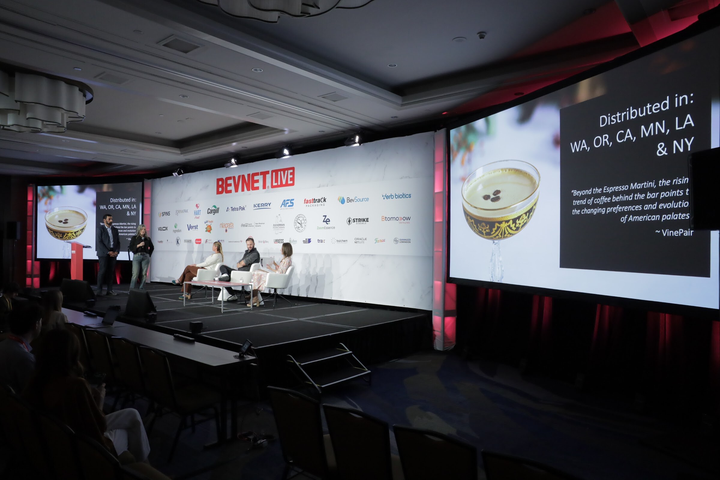 A wide stage shot with a screen showing a cocktail glass and distribution states.