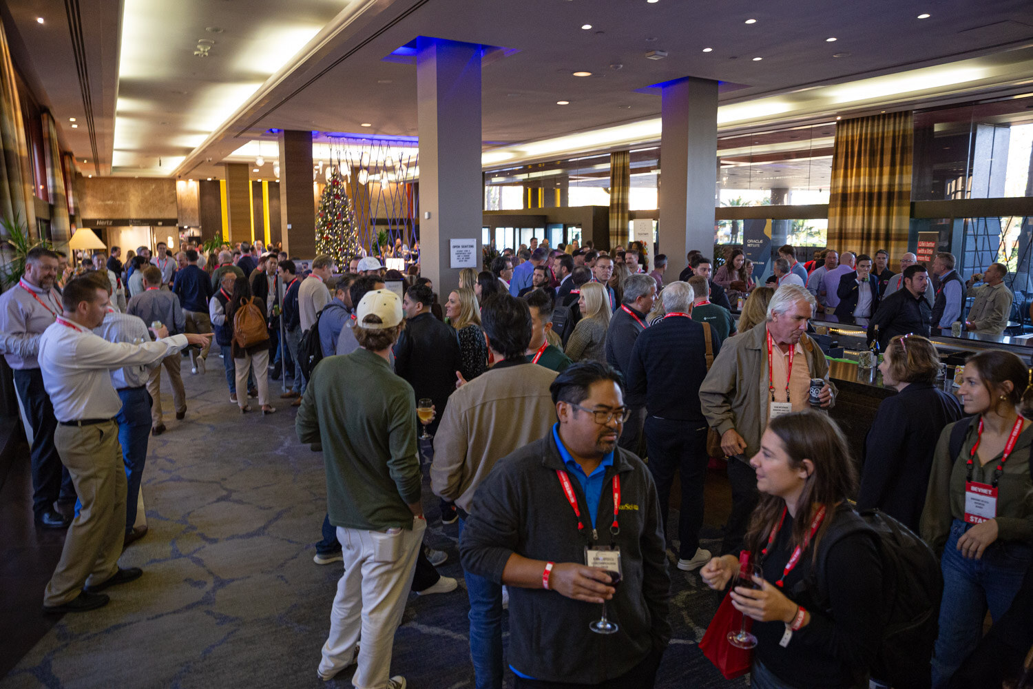 A wide view of a crowded hotel lobby with attendees standing and talking.