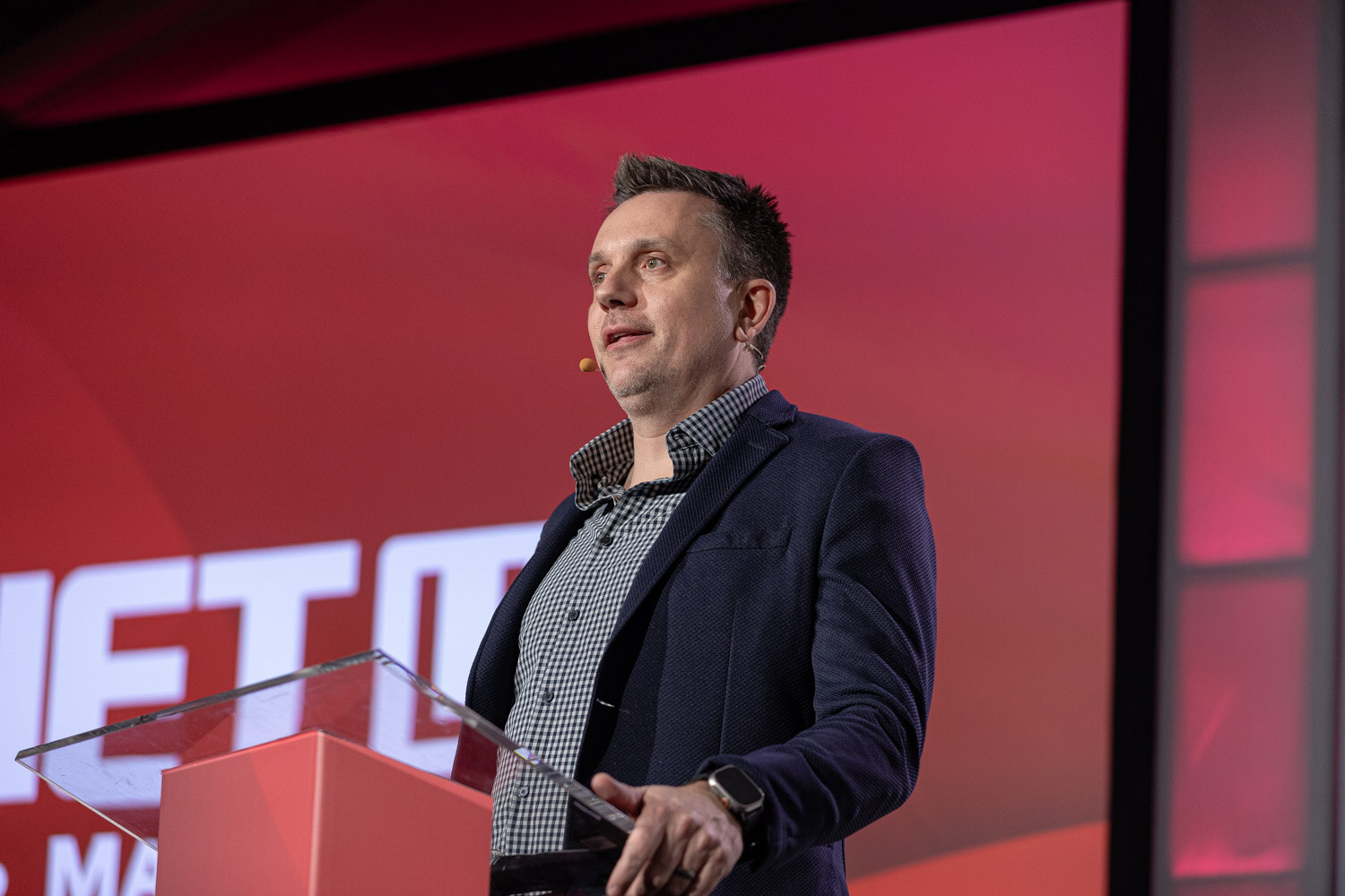 A man in a navy blazer speaks at a red lectern in front of a red BevNET Live Winter 2023 screen.