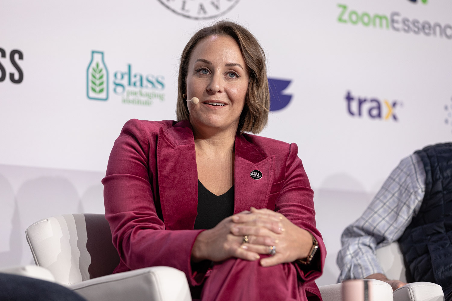 A woman with a bob haircut and magenta velvet blazer sits with her hands in her lap.