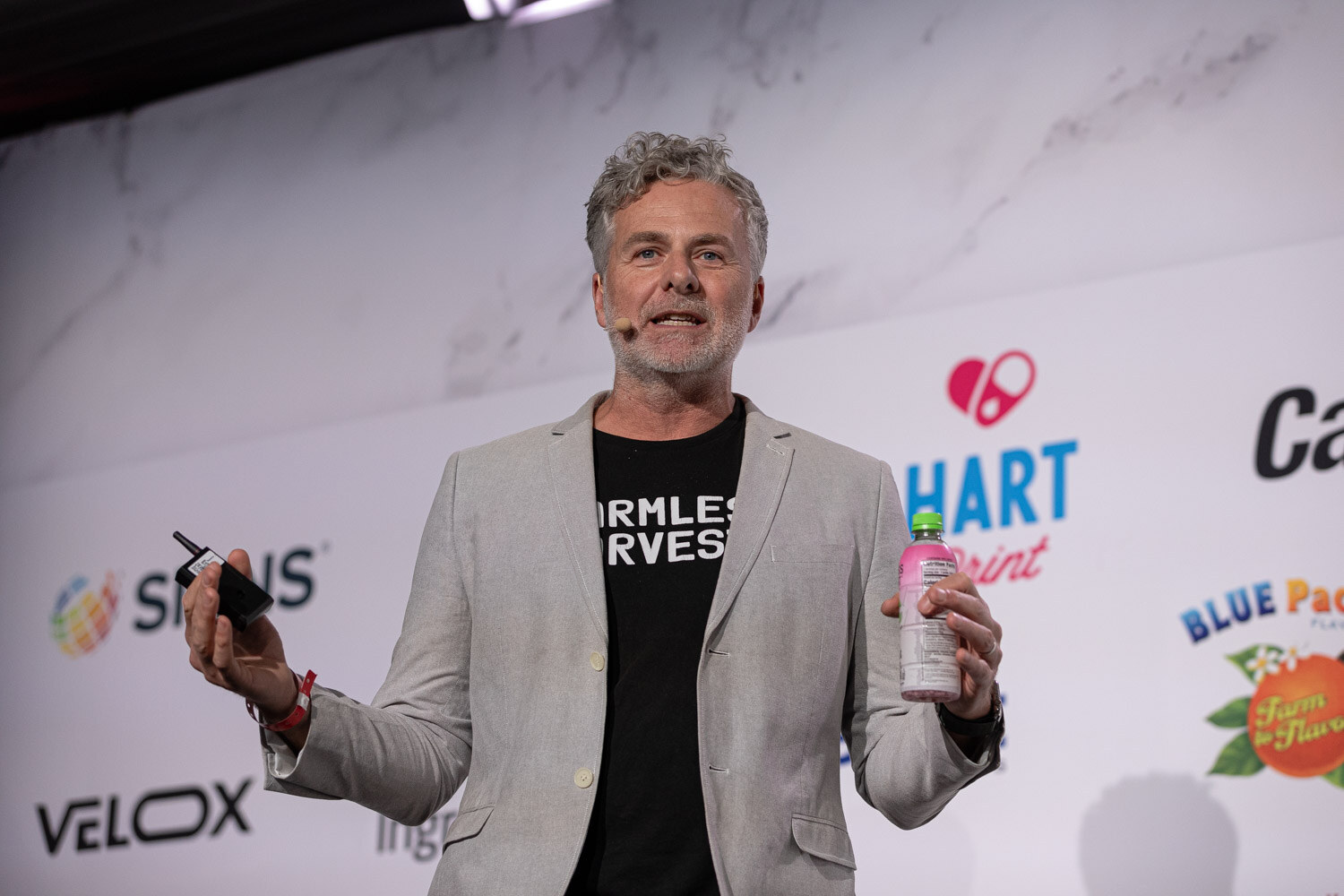 A man in a gray jacket stands on a stage next to a slide about innovation processes.