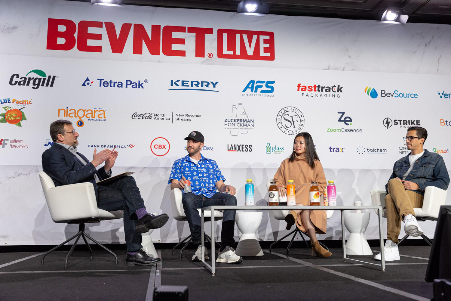 Four people sit in white chairs on a stage in front of a BevNET Live backdrop.
