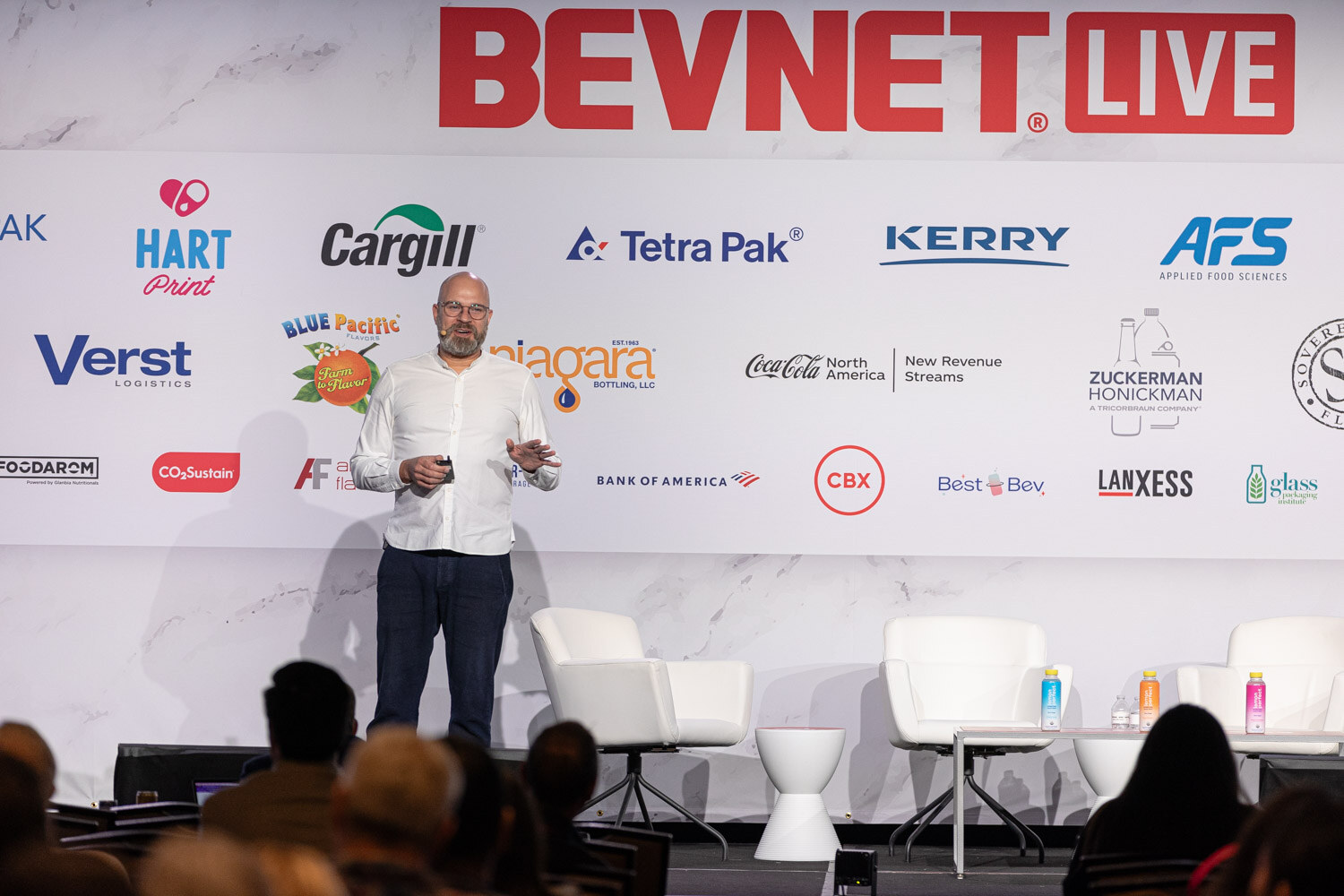 A man in a white shirt stands on the stage in front of a BevNET Live backdrop.