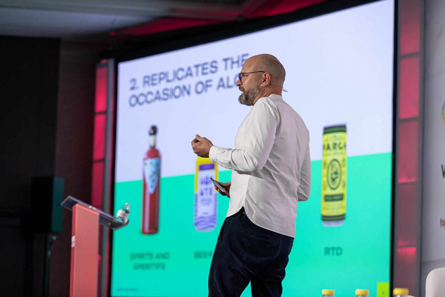 A man in a white shirt gestures in front of a slide titled Replicates the Occasion of Alcohol.