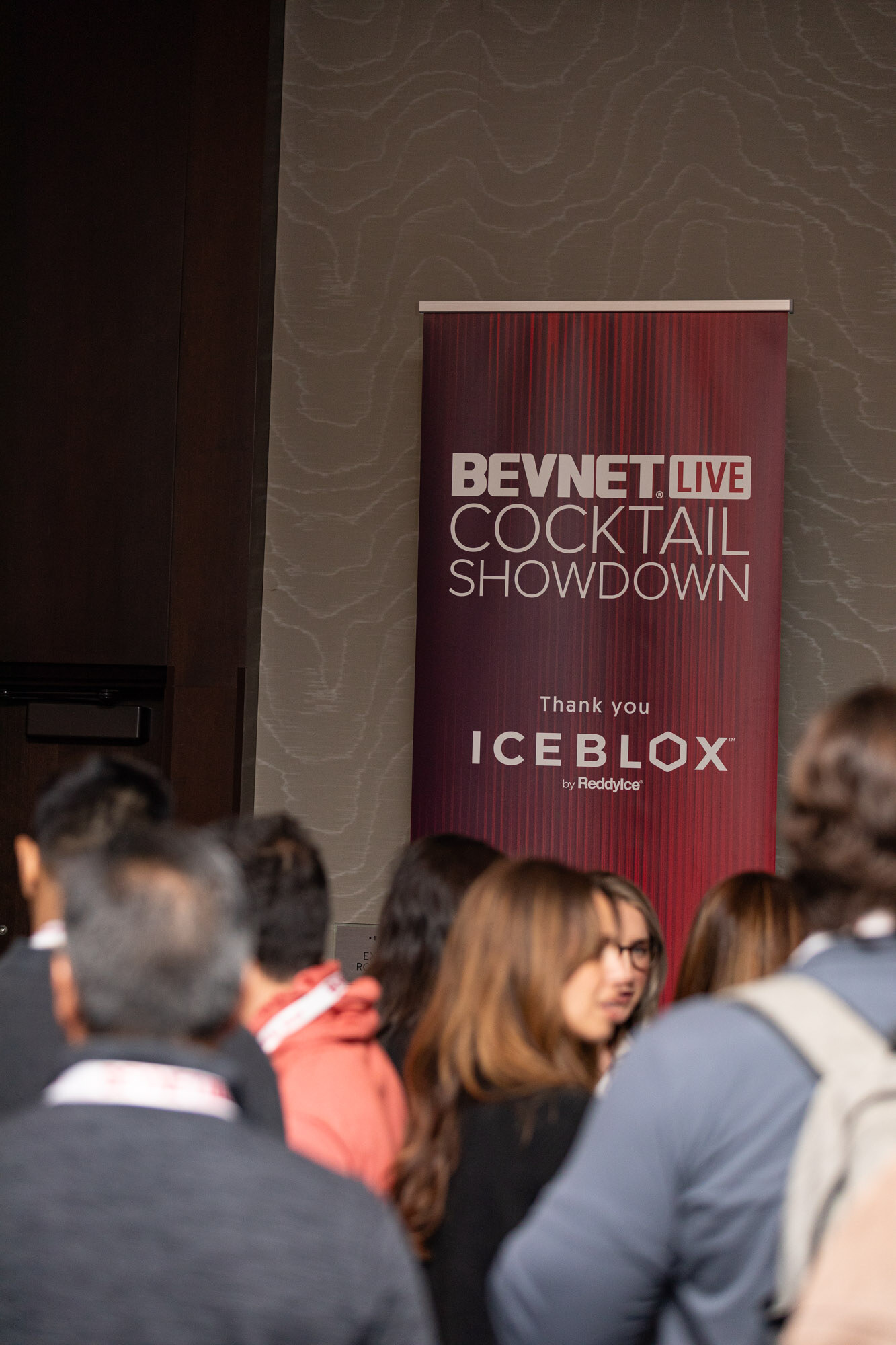 Tall maroon banner reading BevNET Live Cocktail Showdown Thank you Iceblox with a crowd below it.