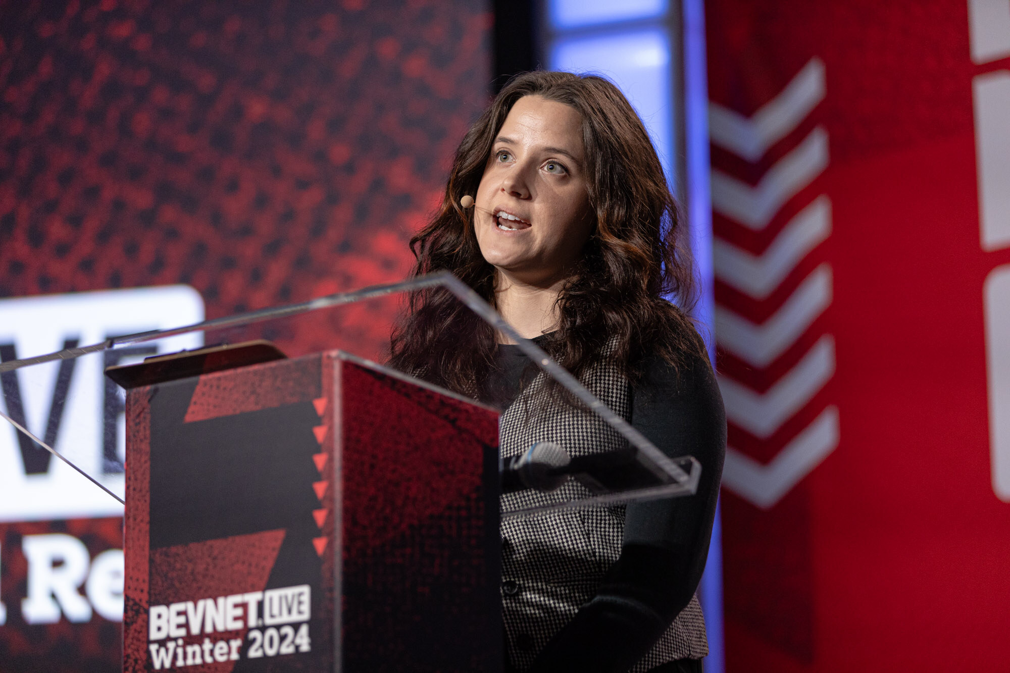 Woman with long dark hair speaks at a podium that reads BevNET Live Winter 2024.