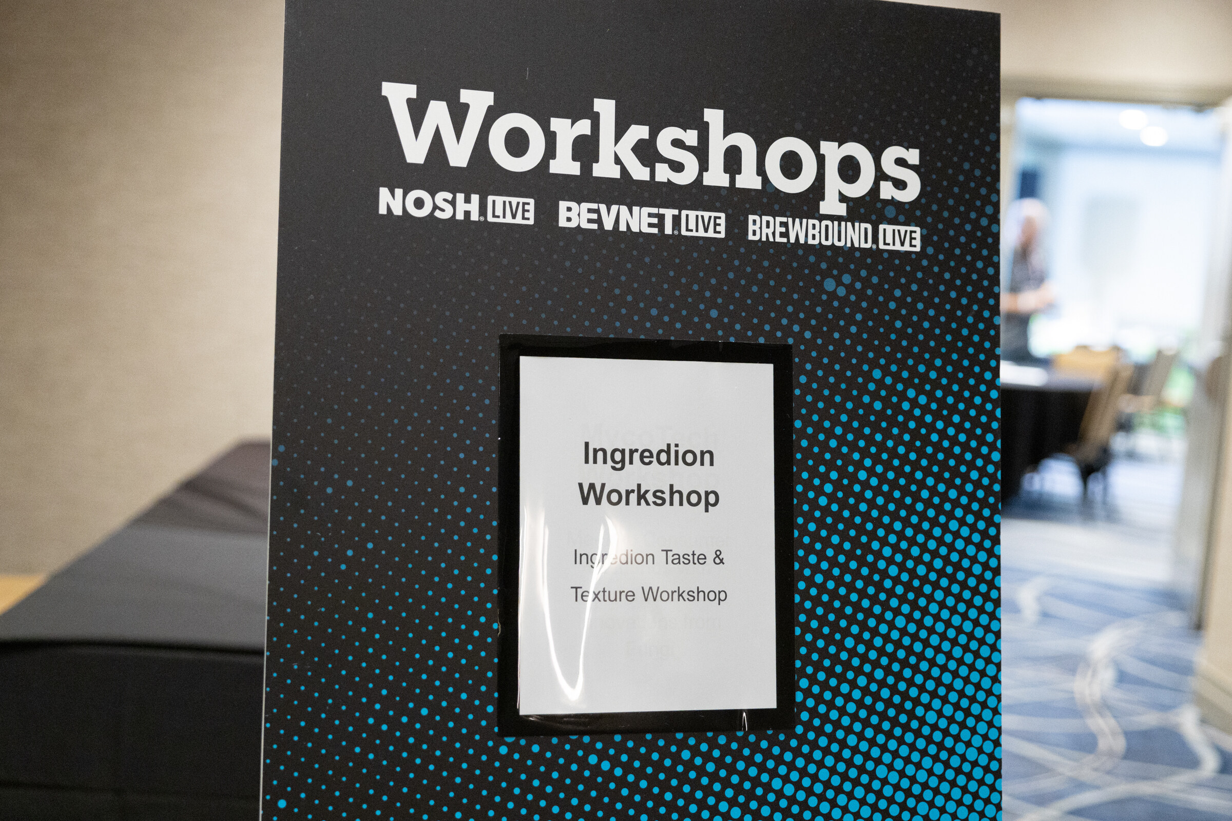 Black sign reading Workshops with NOSH Live, BevNET Live and Brewbound Live logos and a card reading Ingredion Workshop.