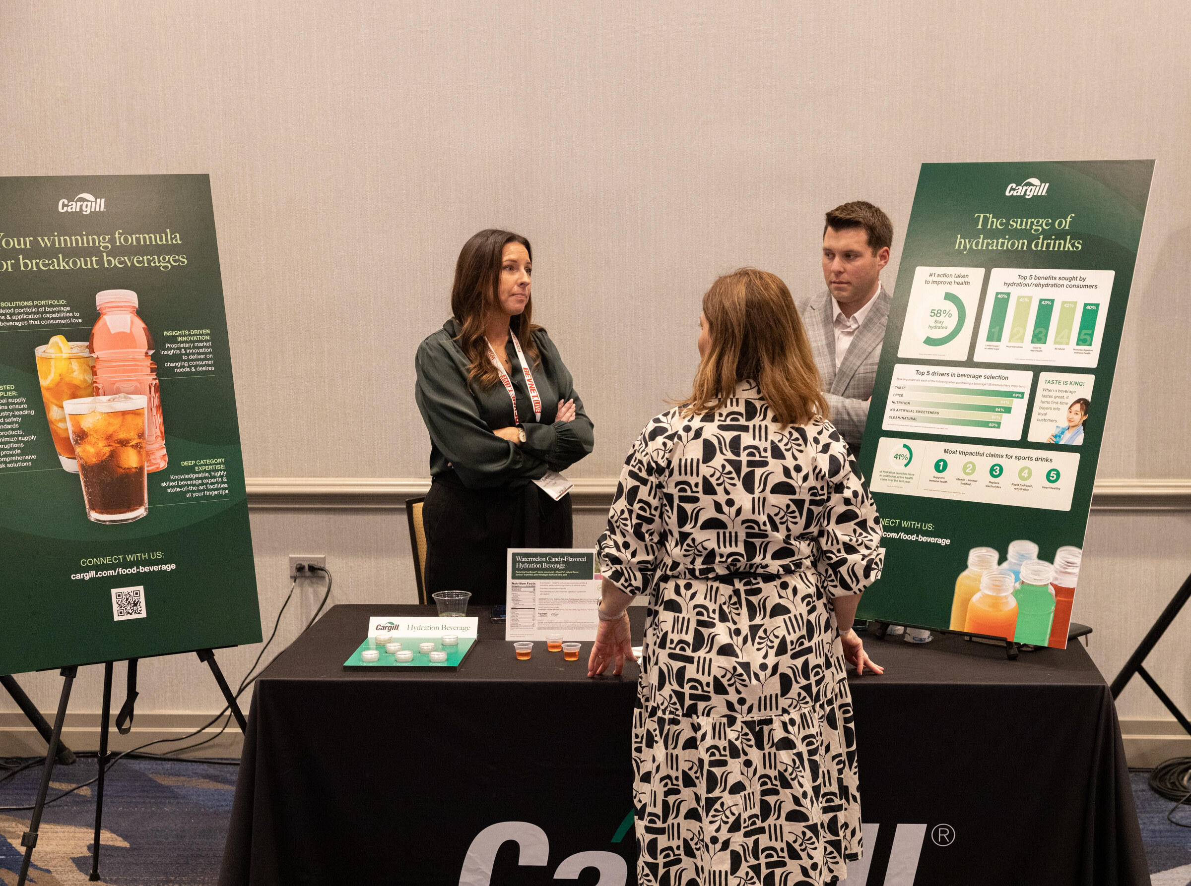 People stand at a black table in front of two green Cargill posters.