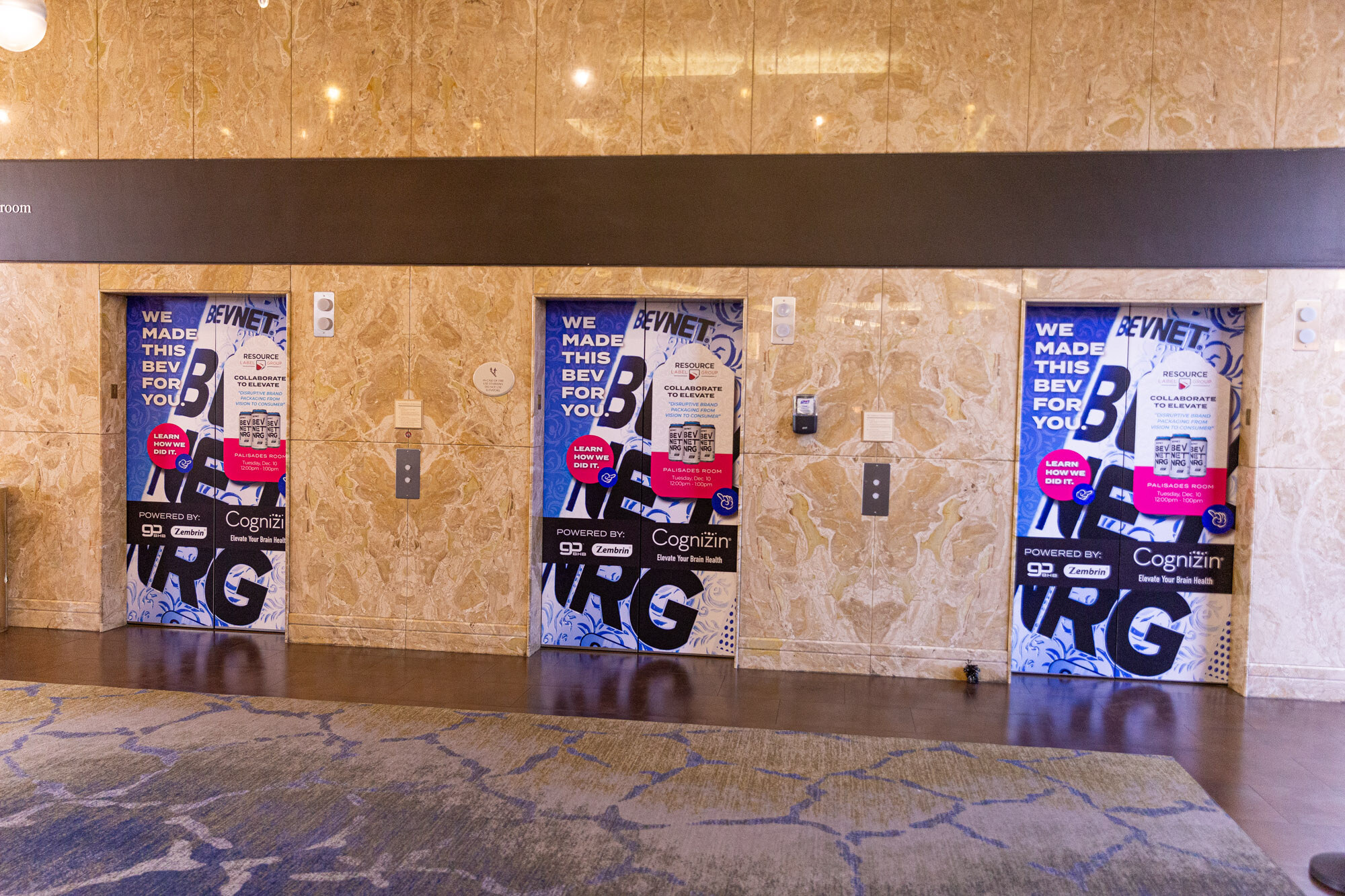 Three elevator doors covered in blue and white graphics with the words We made this bev for you.